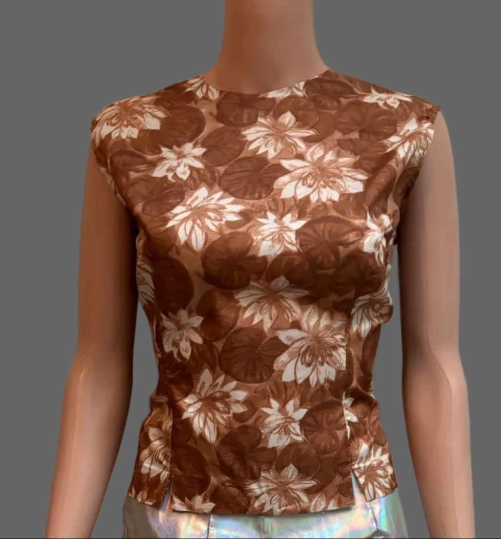 A sleeveless brown top with a white floral pattern and a shiny iridescent silver skirt, displayed on a mannequin in front of a white paneled door.