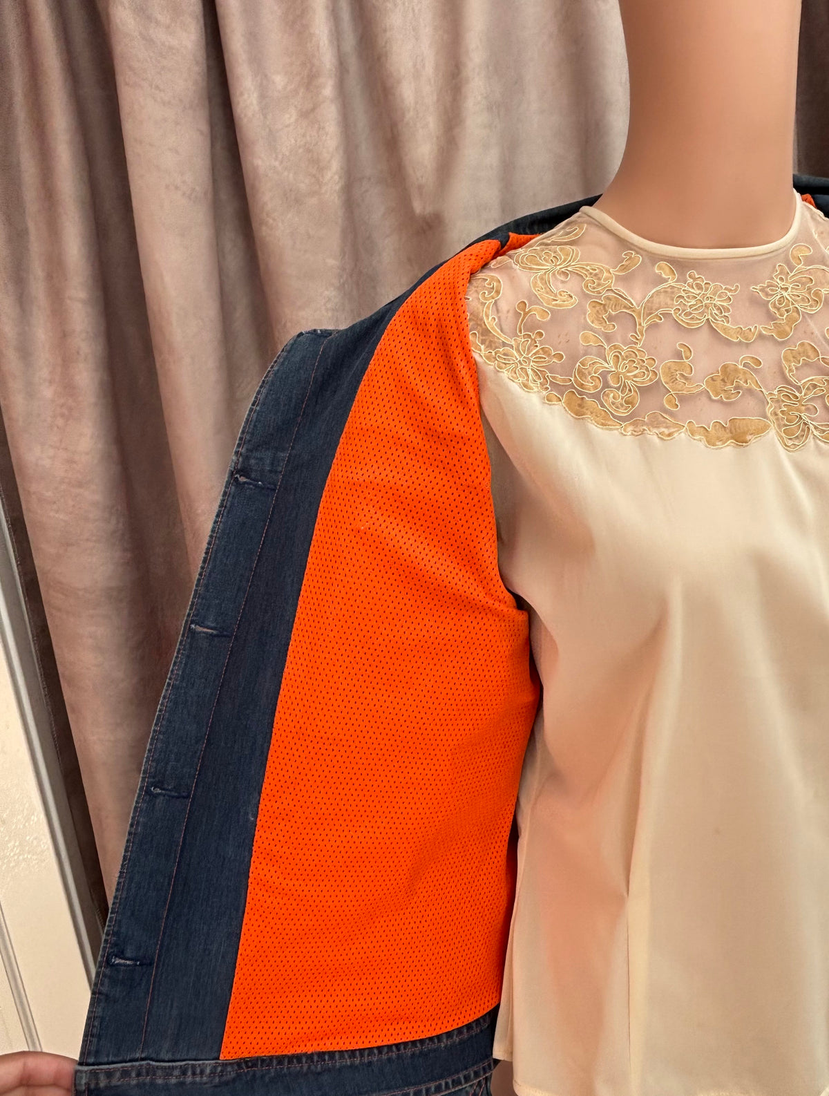 Person wearing a white blouse with gold embroidery and an orange and blue jacket.