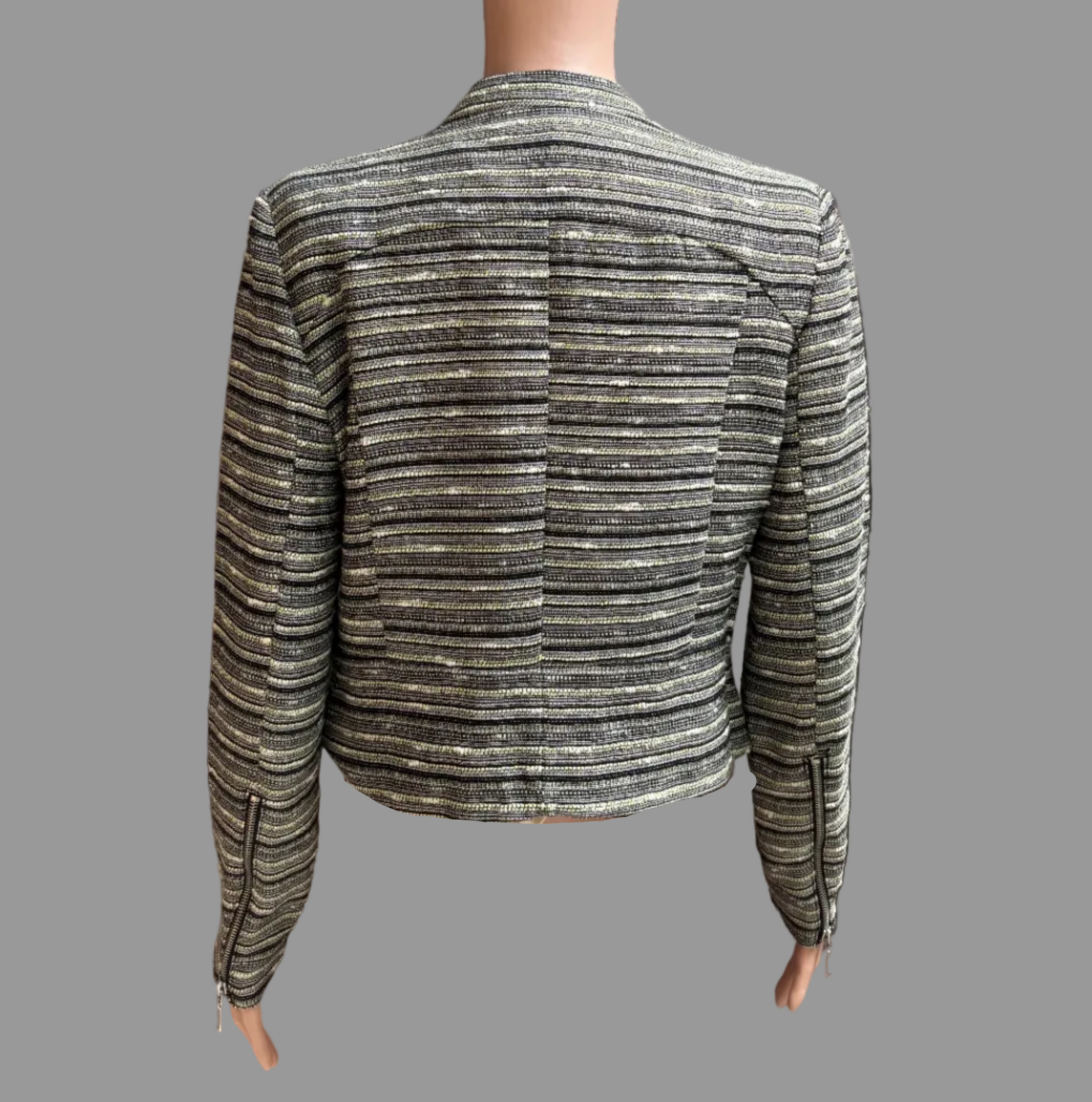 A cropped long-sleeve jacket with horizontal metallic stripes in silver, gold, and black, displayed on a mannequin from the back in front of a brown curtain.