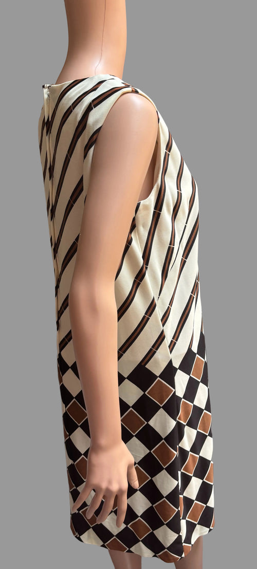Mannequin wearing a sleeveless dress with a geometric pattern against a brown curtain background