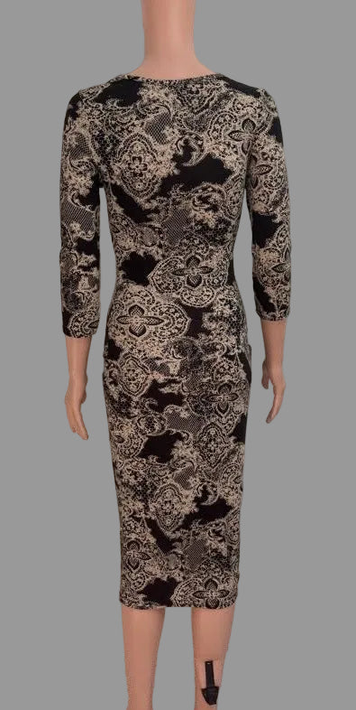 A three-quarter sleeve knee-length dress with an intricate black and beige damask pattern, displayed on a mannequin in front of a white paneled door.